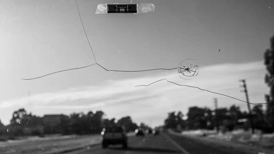 A star chip and a long crack running across a windshield, seen from the driver's seat